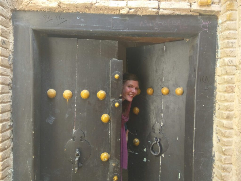 girl looking out of old door